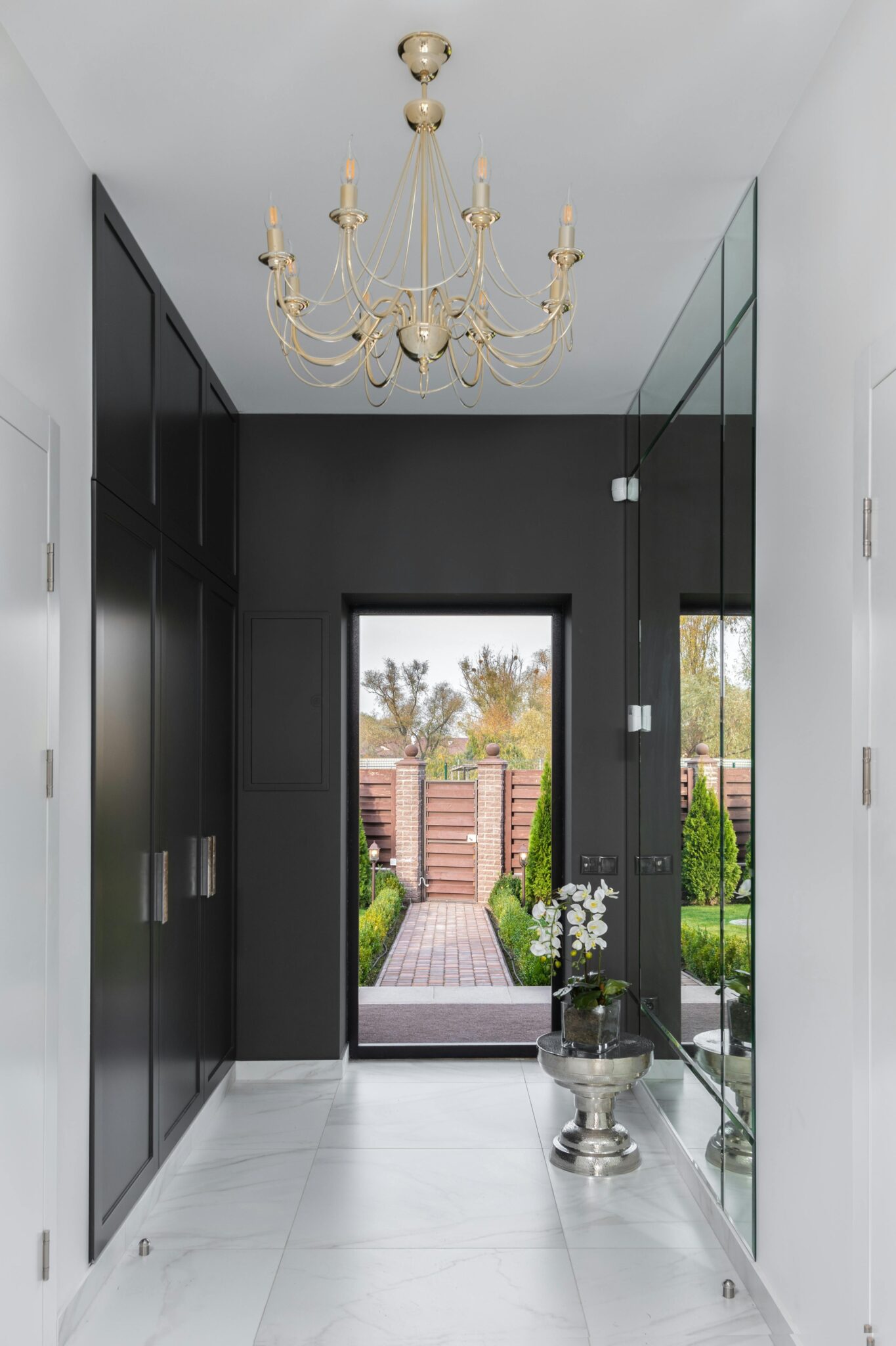 Stylish corridor with marble flooring, chandelier, and outdoor view.
