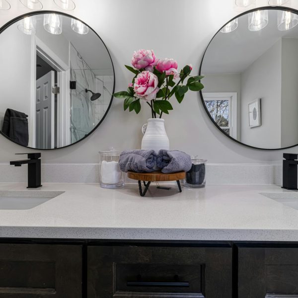 Elegant bathroom vanity setup featuring pink peonies and dual round mirrors.