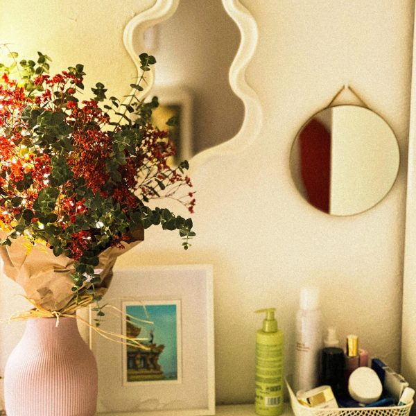 Stylish vanity display with floral arrangement, mirrors, and skincare products.