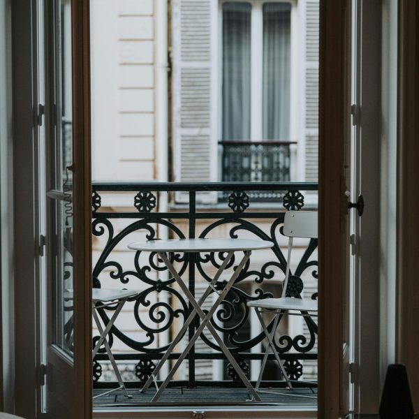 Elegant Parisian balcony featuring intricate ironwork and a cozy seating arrangement. Perfect for urban lifestyle imagery.
