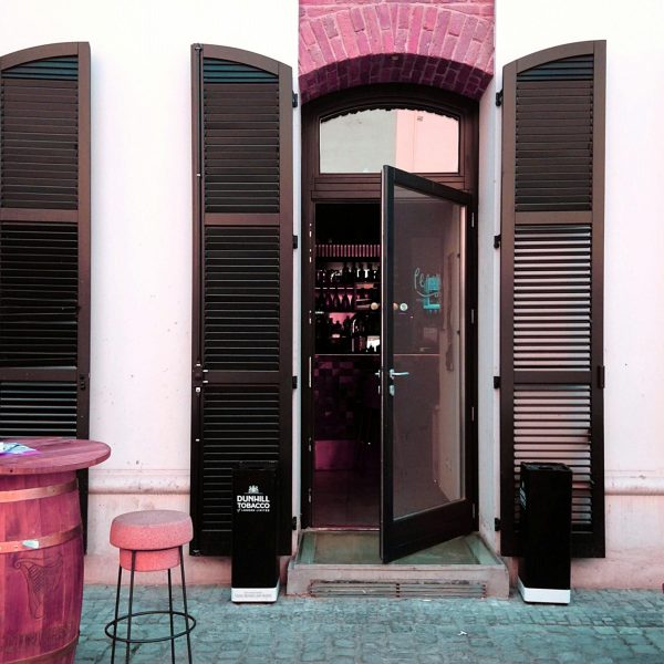 Rustic bar entrance with barrel and stool in Timișoara, Romania, showcasing a warm and inviting atmosphere.