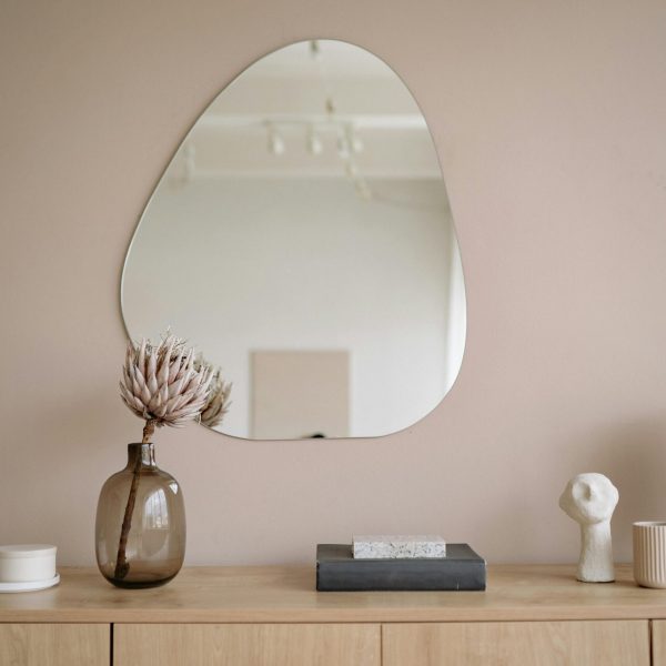 Stylish minimalist interior featuring a mirror, decorative vase, and lamp.