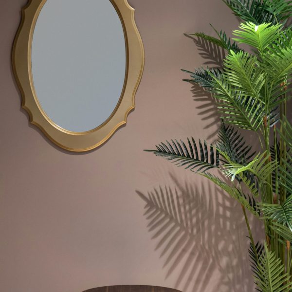 Interior of room with round table near green plant in pot and mirror on beige wall