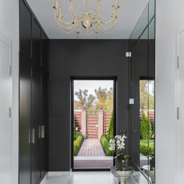Stylish corridor with marble flooring, chandelier, and outdoor view.