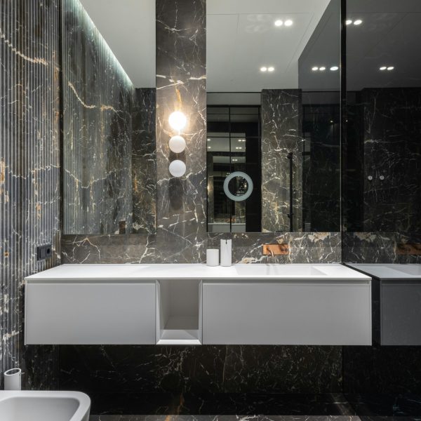 Interior design of modern stylish bathroom with big mirrors and white ceramic tub near sink